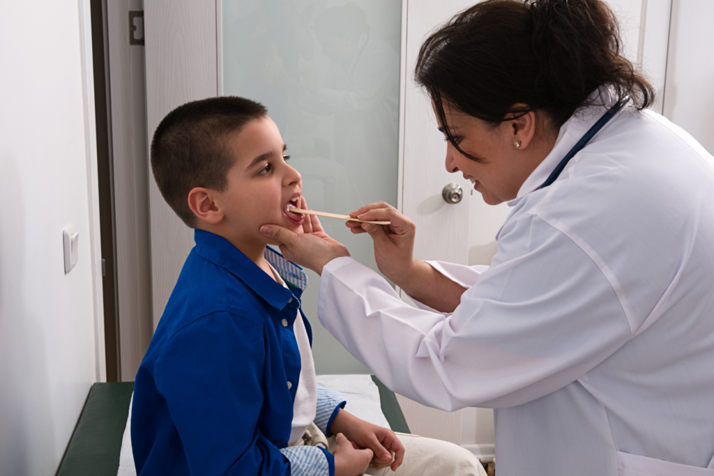 Physician checks child with sore throat.
